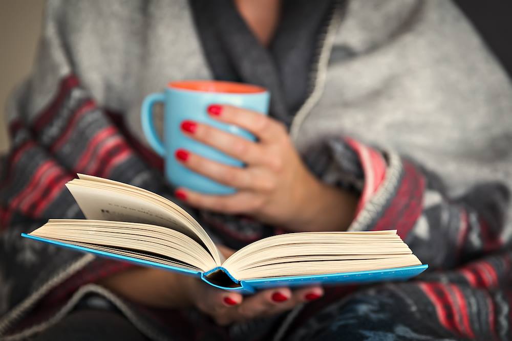 Idee fotografiche autunnali per Instagram: leggi un libro avvolto in un plaid