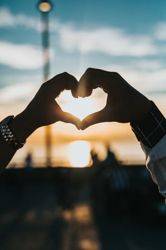 Idee fotografiche autunnali per Instagram - un cuore con le mani al tramonto